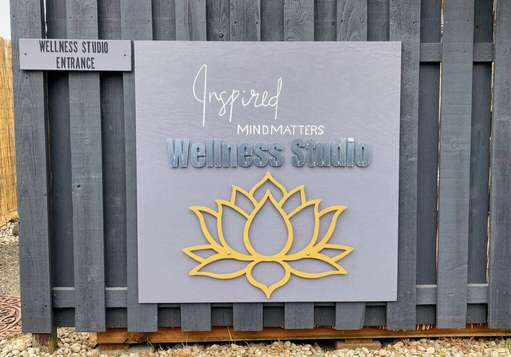 A board of wellness studio with a flower on it